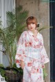 A woman wearing a white kimono standing in front of a door.