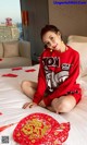 a woman sitting on top of a bed next to a red plate