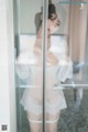 A woman in a white lingerie standing in a shower.