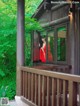 A woman in a red dress standing in the window of a cabin.