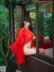 A woman in a red kimono sitting on a window sill.