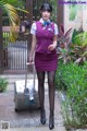 A woman in a purple dress with a suitcase.