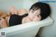 A woman laying in a bathtub with her hands on her hips.