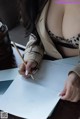 A woman sitting at a table writing on a piece of paper.