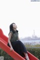 A woman sitting on a red slide in a park.