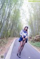 A woman in a school uniform is posing on a road.