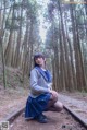 A woman in a school uniform crouching on a train track.