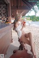 A woman sitting on a bench on the beach drinking a drink.