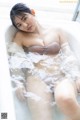 A woman in a bathtub with water on her body.