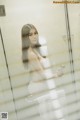 A woman standing in a bathroom next to a shower.