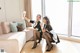 A couple of women sitting on top of a white couch.