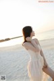 A woman in a white dress standing on a beach.