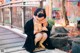 A woman wearing a face mask sitting on a sidewalk.