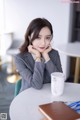 A woman sitting at a table with a cup of coffee.