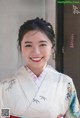 A woman in a kimono smiles at the camera. 