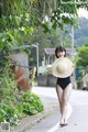 A woman in a black bathing suit and a straw hat walking down a street.