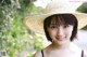 A young woman wearing a straw hat smiles at the camera.