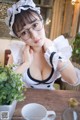 A woman wearing glasses sitting at a table with a cup of coffee.