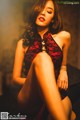 A woman in a red and black lingerie sitting on a chair.