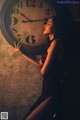 A woman in a red dress holding a large clock.