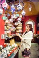 A woman standing in front of a store filled with colorful lamps.