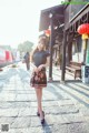 A woman in a black dress is walking down the street.