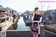 A woman in a black dress standing on a bridge.