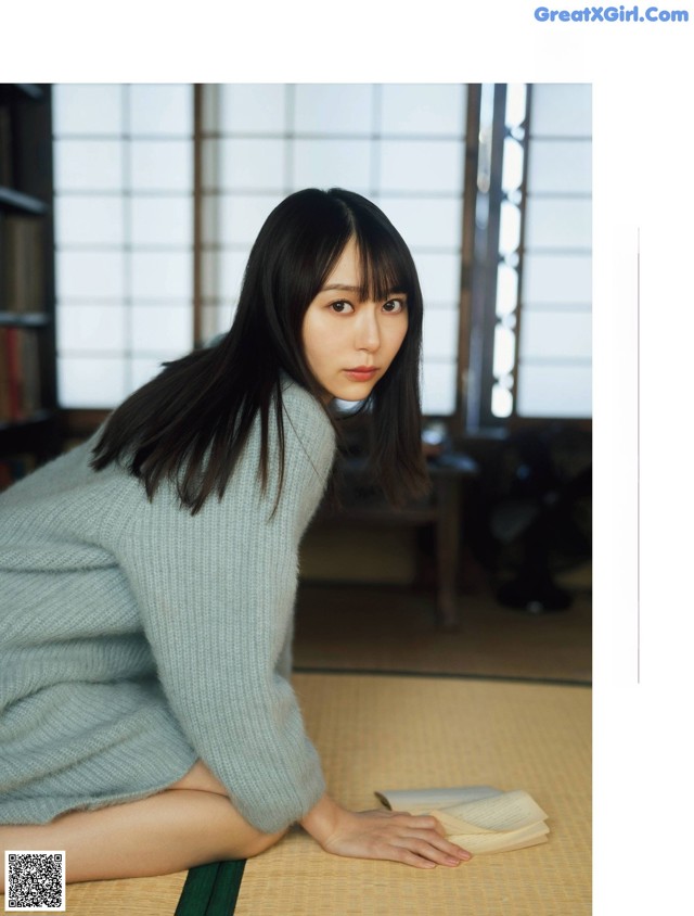 A woman sitting on the floor reading a book.