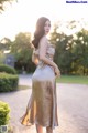 A woman in a gold dress standing on a sidewalk.