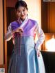 A woman in a blue and purple hanbok is posing for a picture.