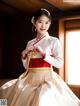 A woman in a white and red hanbok is posing for a picture.