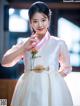 A young girl in a white and pink hanbok poses for a picture.