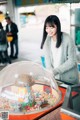 A woman standing in front of a gumball machine.