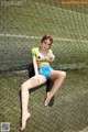 A woman in a bikini sitting on a tennis court.