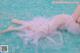 A woman in a pink dress laying on the edge of a pool.