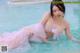 A woman in a pink dress is sitting in a pool.