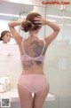 A woman with a tattoo on her back standing in front of a mirror.