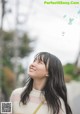 A woman with long black hair smiles at the sky.