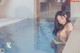 A woman in a yellow bikini sitting in a swimming pool.