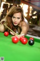 A woman is posing for a picture on a pool table.