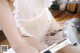 A woman in a white lingerie is washing her legs with a shower head.