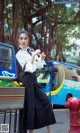 A woman in a white shirt and black skirt standing next to a fire hydrant.