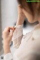 A woman in a white shirt is putting on a ring.