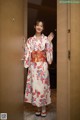 A woman in a kimono standing in front of a door.