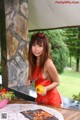 A woman in a red dress holding a knife and a bowl of vegetables.