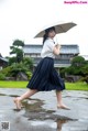 A woman walking in the rain holding an umbrella.