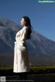 A woman in a white coat standing in front of a mountain.