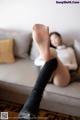 A woman sitting on a couch with her feet up on a table.