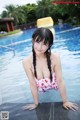 A woman in a bathing suit leaning on the edge of a swimming pool.