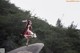 A woman in a red and white dress standing on a rock.